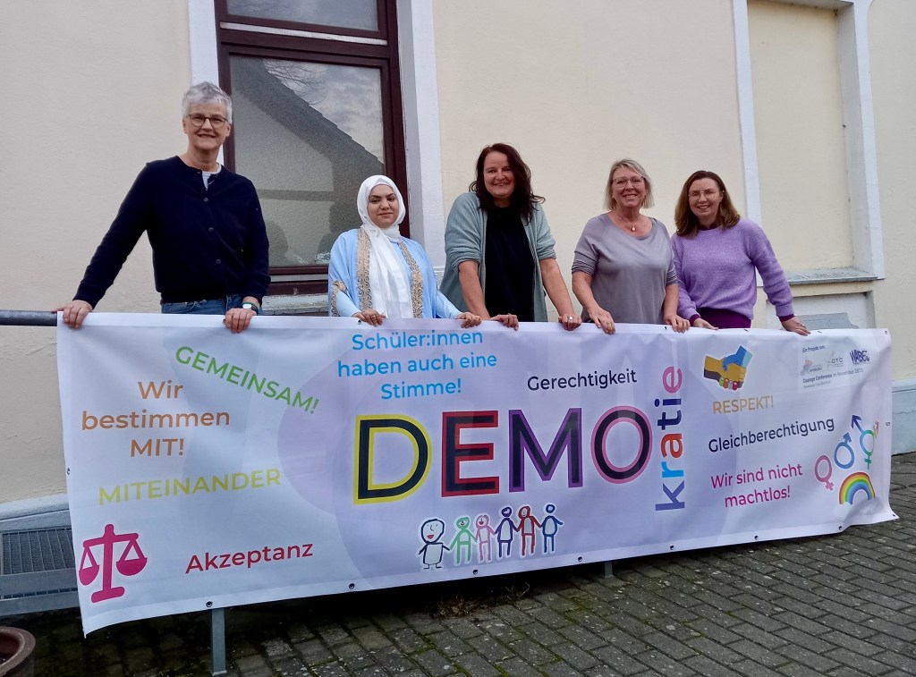 Übergabe des Banners vom Team der Koordinierungsstelle Migration und Teilhabe an das Team vom Haus der Generationen